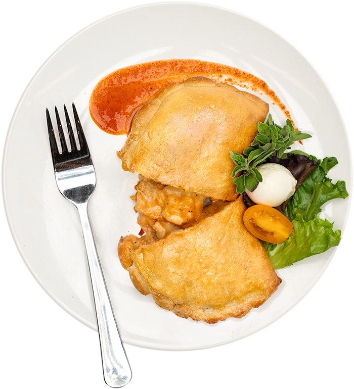 Image of the Enchilada Empanada calzone product on a plate, with other assorted foods