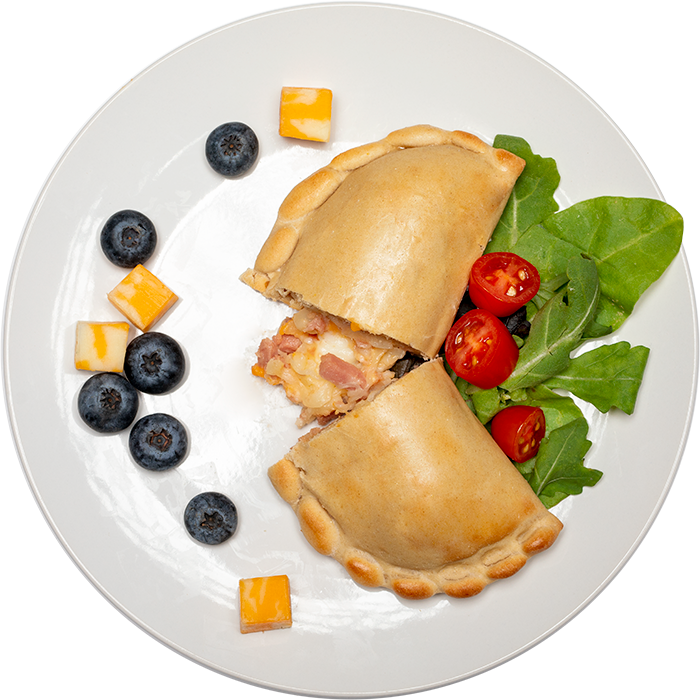 Image of the Turkey Ham & Cheese calzone product on a plate, with other assorted foods